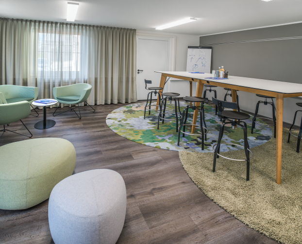 Moderner Besprechungsbereich mit Stehtisch, Barhockern und gemütlicher Lounge-Ecke in den Büroräumen der Veproline GmbH