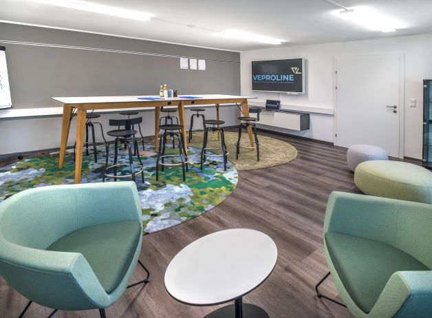 Flexibler Workshopraum mit langem Besprechungstisch, Hockern und Loungesesseln