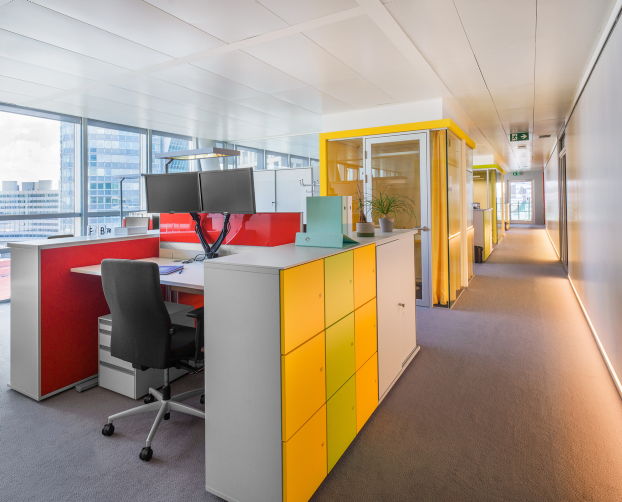 Großraumbüro mit bunten Schränken, modernen Arbeitsplätzen und gelber Akustikbox bei STRABAG Wien