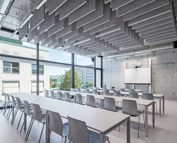 Raum mit Konferenztischen, grauen Akustikpaneelen und Blick nach draußen