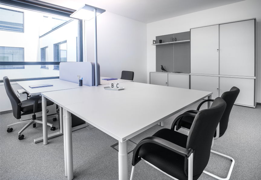 Offenes Büro mit mehreren Arbeitsplätzen, Stauraumelementen, Beleuchtung und direktem Außenlicht