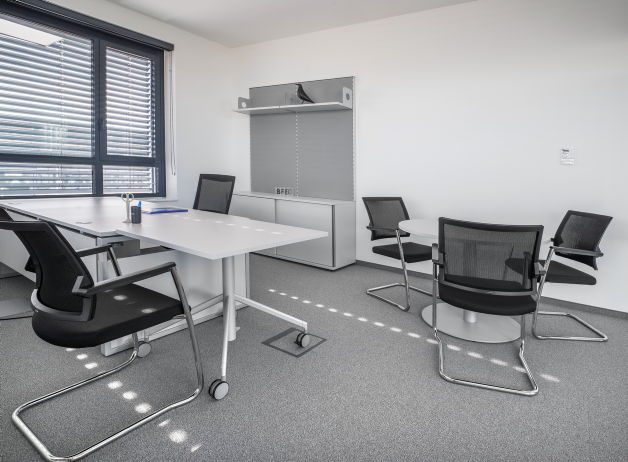 Büro mit Besprechungstisch und schwarzen Freischwingerstühlen, lichtdurchflutet und modern eingerichtet