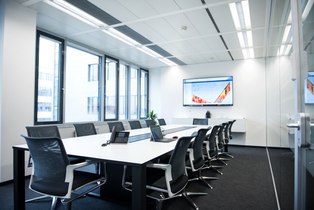 Konferenzraum mit Konferenztisch s180 mit schwarzem Tischgestell und weißer Tischplatte sowie Trennwänden RS11 mit Beklebung.