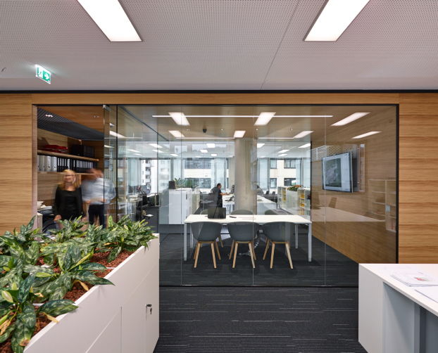 Modernes Großraumbüro mit Meetingraum aus Glas, Pflanzen und offenen Arbeitsplätzen