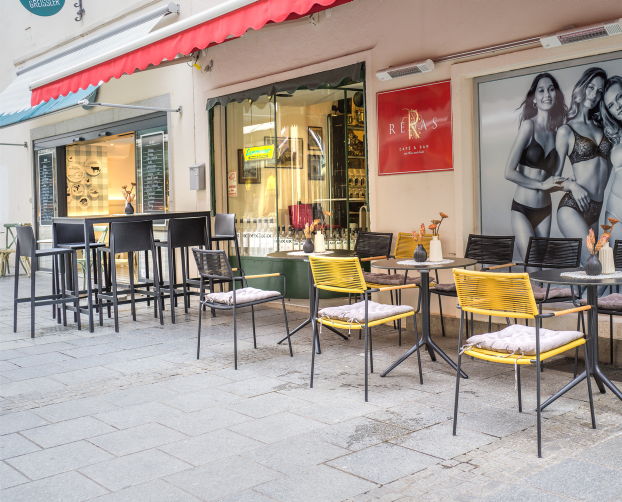 Außenbereich des Café Resas mit modernen Tischen und gelben Stühlen von hali – stilvoller Platz zum Verweilen.