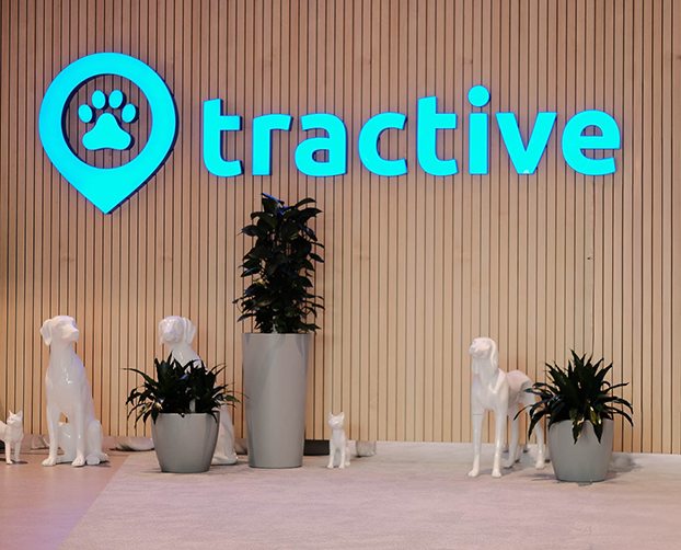 Moderner Empfangsbereich bei Tractive mit großem Markenlogo, Pflanzen und weißen Dekofiguren.