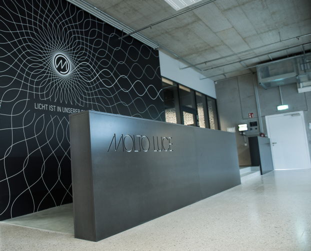 Moderner Empfang mit dunklem Tresen und markanter Wandgestaltung im Büro von Molto Luce