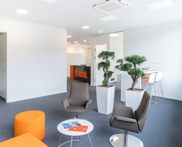 Moderne Lounge mit Sitzmöbeln, hohen Pflanzgefäßen und Blick auf den Empfang