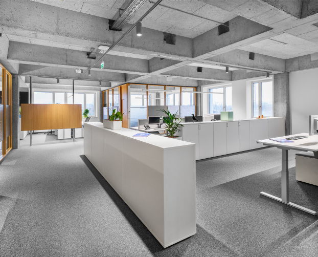 Offene Bürofläche mit weißen Schränken und ergonomisch eingerichteten Arbeitsplätzen