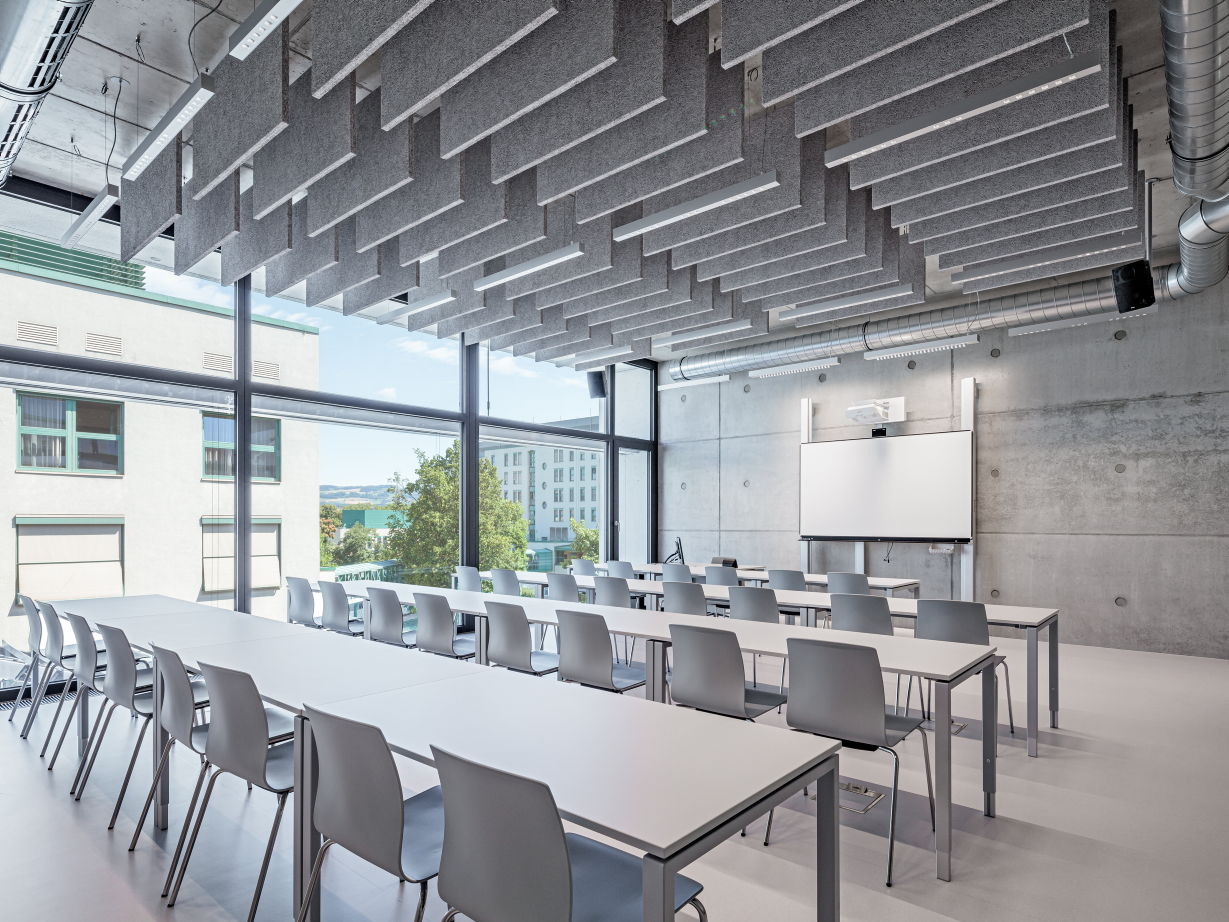 Raum mit Konferenztischen, grauen Akustikpaneelen und Blick nach draußen