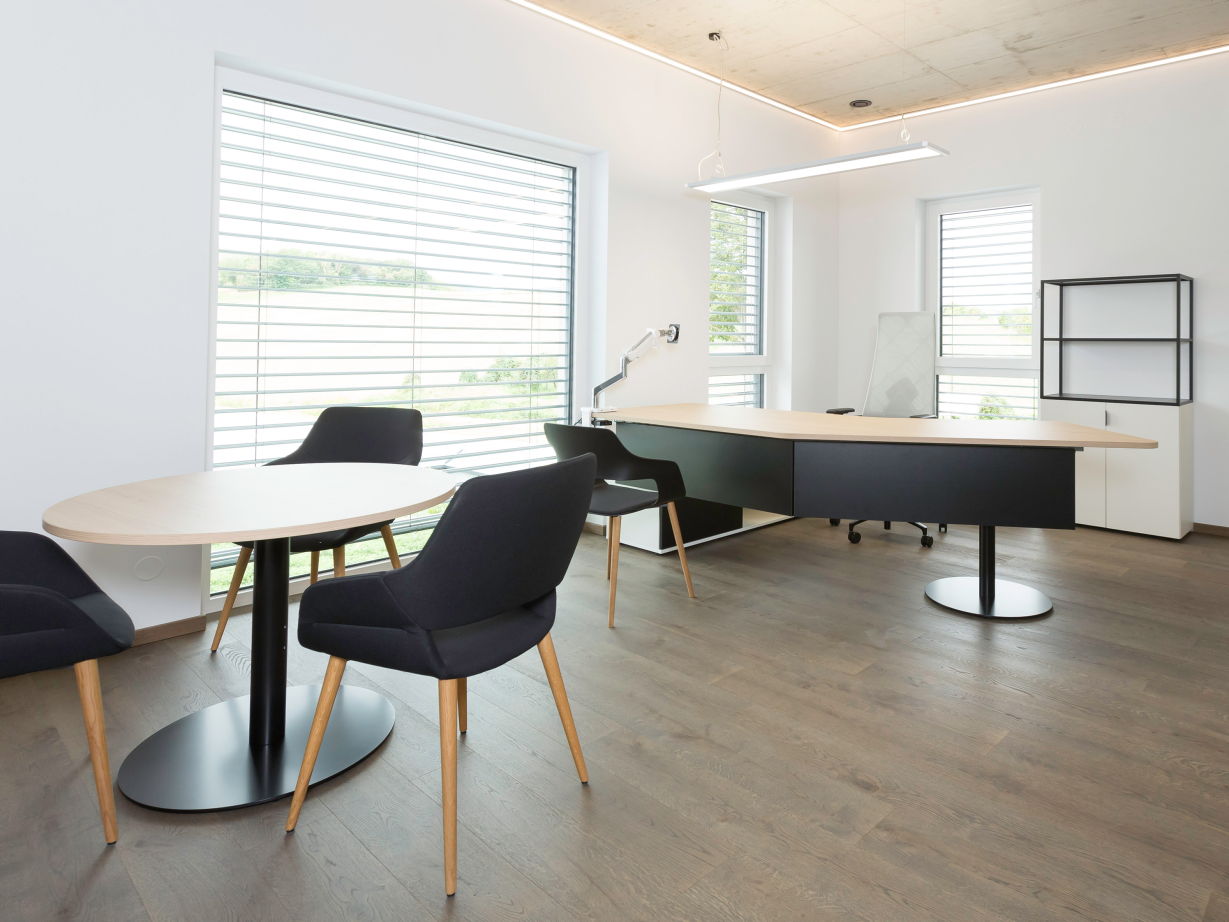 Modernes Büro mit Schreibtisch und rundem Besprechungstisch bei Schöll-Bau GmbH, eingerichtet mit hali Möbeln in elegantem Design.