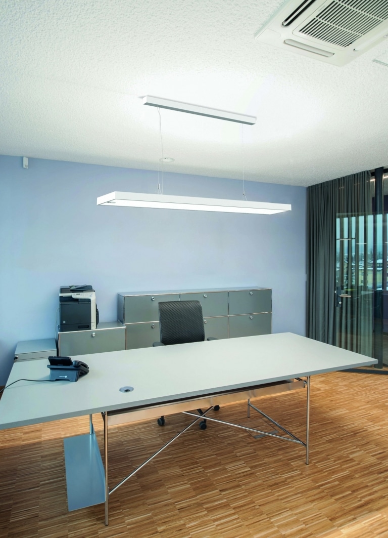 Arbeitsplatz mit Hängeleuchte System 01 von Molto Luce in weißer Ausführung. Die rechteckige Hängelampe verbreitet Licht im ganzen Büroraum.