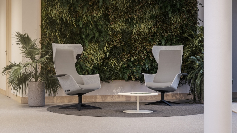Loungebreich ausgestattet mit Besucherstühlen Wooom der Marke Klöber mit hoher Sitzlehne, Armlehnen, sitzschale in grau und schwarzem Gestell.