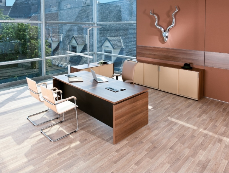 Ambientebild Managerbüro mit Arbeitstisch in Holzoptik mit Stauraum in Brauntönen gehalten.