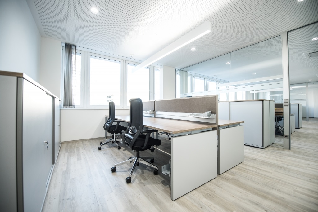 Doppelarbeitsplatz mit Arbeitstischen der Serie s500 in weiß und Tischplatte Melamin in Nussoptik sowie Sichtschutz mit Organisationsschiene und Pinnfläche in beige.